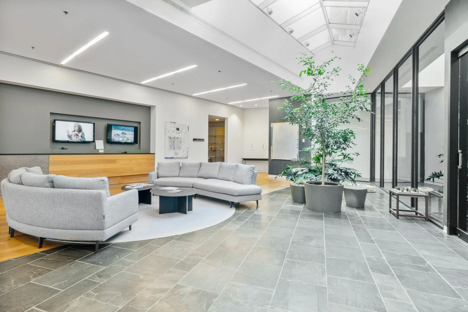 Bright, clean modern office lobby with light gray seating and potted plants